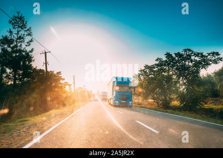 Fahrzeug in Bewegung auf der Landstraße im Sonnenuntergang Sonne Sonnenschein natürliches Sonnenlicht. Zugmaschine, Prime Mover, Triebfahrzeuge auf der Landstraße in Europa. Busin Stockfoto