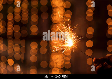 Abstrakte Sparkelrs Hintergrund mit hellgelben Bokeh, hellen festlichen Diwali, Weihnachten, Frohes Neues Jahr Hintergrund stock Bild. Mann mit Wunderkerzen. Stockfoto