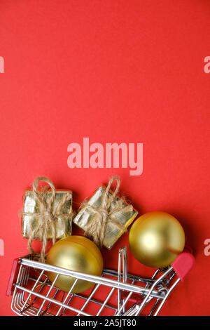 Goldene Kugeln und des Neuen Jahres Geschenke mit Garn in Spielzeug Warenkorb auf rotem Hintergrund mit kopieren. Vertikale. Stockfoto
