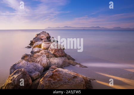 Pier/Steg von Fels und Stein, playa de muro, Alcudia, Mallorca, Spanien, Sonnenaufgang über Berge, schöne glatte Meer. Stockfoto