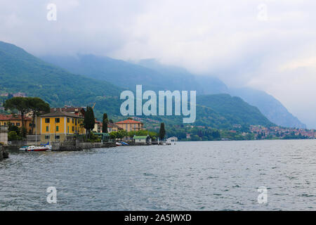 Comer see und Gebäude auf Küste und Alpen Berg mit Wolken im Hintergrund. Stockfoto