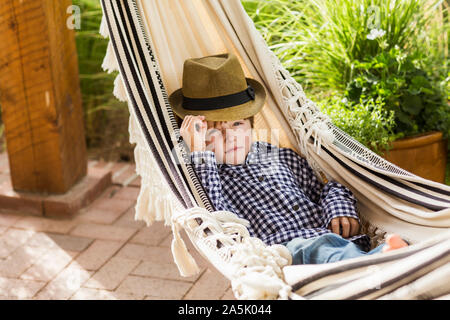 Portrait von 6 Jahre alten Jungen liegen in der Hängematte auf der Veranda Stockfoto