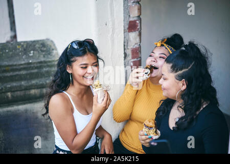 Junge Frau mit jugendlichen Schwestern essen Kuchen in der Tür Stockfoto