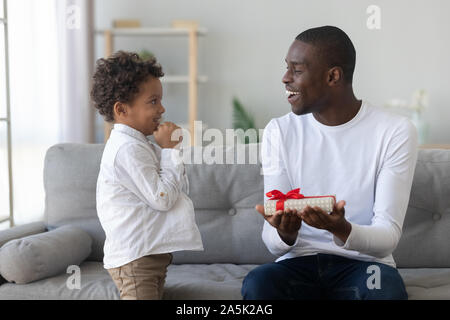 Wenig biracial Junge vorhanden Geschenkbox aufgeregt zu Vati Stockfoto