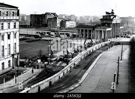 Berliner Mauer verstärkt. Unter den wachsamen Augen der kommunistischen Polizei, ostdeutschen Arbeiter in der Nähe von Brandenburger Tor verstärken die Mauer teilt die Stadt. Seit der Errichtung der Mauer am 13. August 1961, stoppen Sie den Ostdeutschen in West Berlin, die Ostdeutschen Kommunisten haben Bunker, Strahler und feuern und Beobachtung Beiträge hinzugefügt. Stockfoto