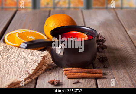 Alte Metall pan Pot an leckeren Glühwein mit Topf mit Gewürzen und Orange Früchte auf hölzernen Tisch. Stockfoto