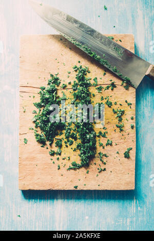 Wie serie Kochen 101 Guide, wie man gehackte Petersilie, Blick von oben auf die frische Petersilie auf einem cutboard mit Messer und Mandoline auf einem urigen, flach Comp Stockfoto