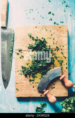 Wie serie Kochen 101 Guide, wie man gehackte Petersilie, Blick von oben auf die frische Petersilie auf einem cutboard mit Messer und Mandoline auf einem urigen, flach Comp Stockfoto