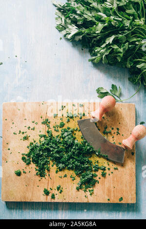 Wie serie Kochen 101 Guide, wie man gehackte Petersilie, Blick von oben auf die frische Petersilie auf einem cutboard mit Messer und Mandoline auf einem urigen, flach Comp Stockfoto