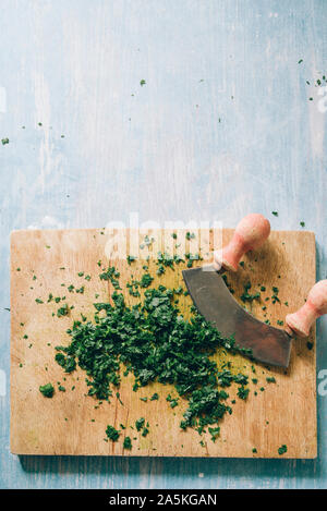 Wie serie Kochen 101 Guide, wie man gehackte Petersilie, Blick von oben auf die frische Petersilie auf einem cutboard mit Messer und Mandoline auf einem urigen, flach Comp Stockfoto