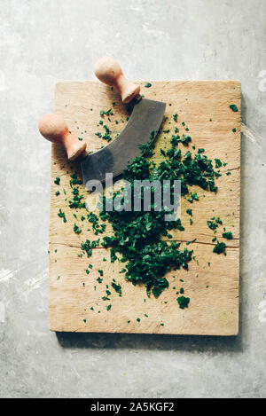 Wie serie Kochen 101 Guide, wie man gehackte Petersilie, Blick von oben auf die frische Petersilie auf einem cutboard mit Messer und Mandoline auf einem urigen, flach Comp Stockfoto