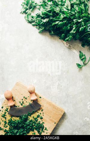 Wie serie Kochen 101 Guide, wie man gehackte Petersilie, Blick von oben auf die frische Petersilie auf einem cutboard mit Messer und Mandoline auf einem urigen, flach Comp Stockfoto