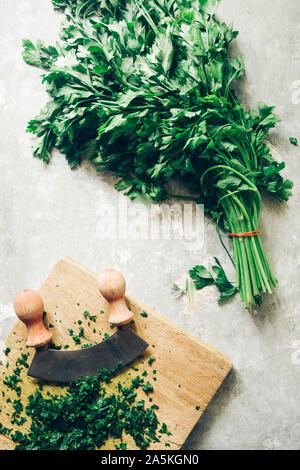 Wie serie Kochen 101 Guide, wie man gehackte Petersilie, Blick von oben auf die frische Petersilie auf einem cutboard mit Messer und Mandoline auf einem urigen, flach Comp Stockfoto