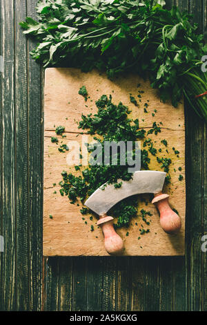 Wie serie Kochen 101 Guide, wie man gehackte Petersilie, Blick von oben auf die frische Petersilie auf einem cutboard mit Messer und Mandoline auf einem urigen, flach Comp Stockfoto