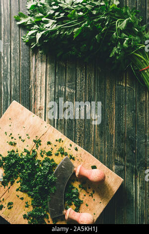 Wie serie Kochen 101 Guide, wie man gehackte Petersilie, Blick von oben auf die frische Petersilie auf einem cutboard mit Messer und Mandoline auf einem urigen, flach Comp Stockfoto