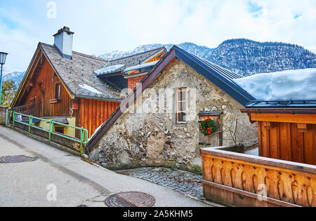 Das alte Holz- und Steinhäuser in der hügeligen Straße der kleinen Bergstadt Hallstatt, Salzkammergut, Österreich Stockfoto