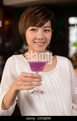 Lächelnde junge Frau Rosa Cocktail genießen. Stockfoto
