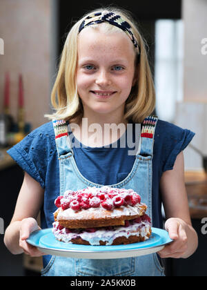 Mädchen backen einen Kuchen, hausgemachten Kuchen mit Himbeeren auf die Oberseite in Küche, Porträt Stockfoto