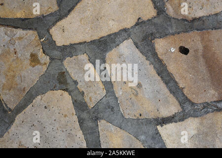 Gehweg aus asymmetrischen braunen Felsen und einige Graue details in zwischen ihnen. Schönen architektonischen Detail mit schöner Struktur. Hintergrund Foto. Stockfoto