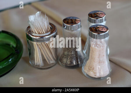 Zucker, Salz und Pfefferstreuer aus Glas und einige Zahnstocher auf eine Tabelle mit beige Tischdecke. Nahaufnahme Farbe Bild der Küche details. Stockfoto