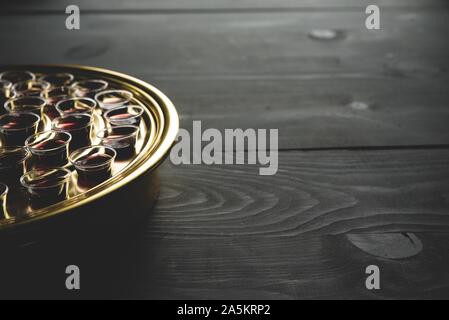 Nahaufnahme eines Tabletts mit roten alkoholischen Schüssen auf Eine schwarze Holzoberfläche Stockfoto