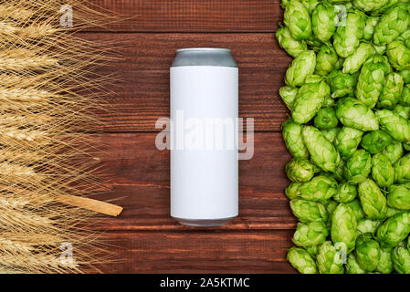 Ein Bier kann, grüne Kegel von Hopfen und Getreide auf Holz- Hintergrund. Ansicht von oben. Freier Platz für Text. Stockfoto