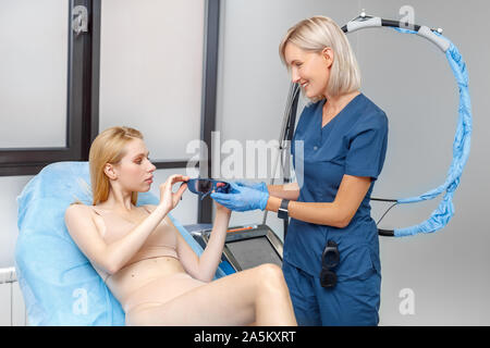Kosmetologie Service. Junge Frau von Schönheit Klinik liegen während der Doktor ihr Sicherheit geben Gläser smilign positiv Stockfoto