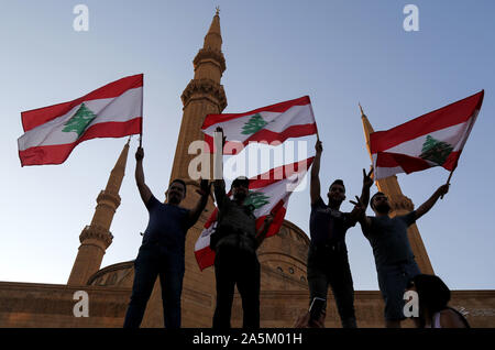 Beirut, Libanon. Okt, 2019 21. Demonstranten Wave die libanesische Flagge während eines Protestes in Beirut in der Innenstadt, nur wenige Stunden nach dem libanesischen Ministerpräsidenten Saad al-Hariri angekündigter Wirtschaftsreformen, die die schwierigen wirtschaftlichen Situationen erleichtern könnte. Demonstranten, die in den Straßen über dem Land für die 5 geraden Tag wurden, weigerte sich Hariri Entscheidungen und forderten den Rücktritt der Regierung. Credit: Marwan Naamani/dpa/Alamy leben Nachrichten Stockfoto