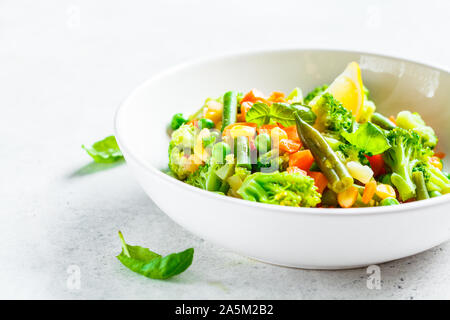 Gedämpftes Gemüse (Brokkoli, Möhren, Bohnen, Erbsen, Mais) in einer weißen Platte. Gesunde Ernährung Essen Konzept. Stockfoto