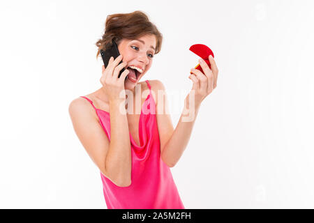 Aufgeregt Braut mit einem Ehering in ihren Händen, am Telefon zu sprechen, Foto eines Mädchens auf einem weißen Hintergrund isoliert Stockfoto