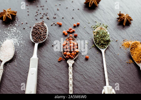 Eine Auswahl von Kochen Gewürze auf vintage Löffel auf einer Schiefertafel board Stockfoto