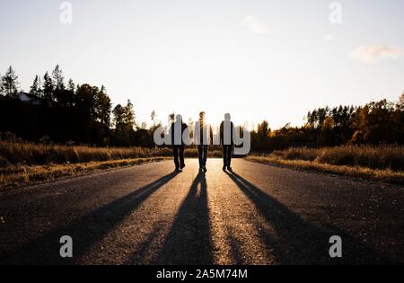 Silhouette der Familie auf einer Landstraße bei Sonnenuntergang Stockfoto