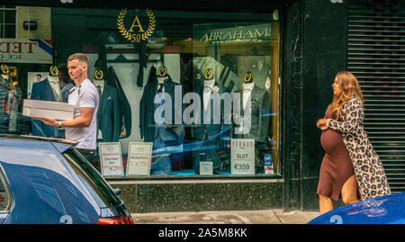 Mann, der Box vorbei gehen. shop Verkauf Anzug, schwangere Frau hinter, St Stephen's Green, Dublin, Irland, Stockfoto