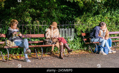 Frauen lesen, Paar küssen Auf Parkbank, Dublin, Irland Stockfoto