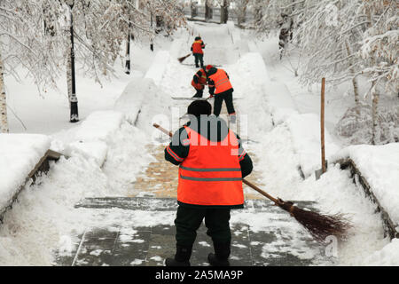 Kiew, Ukraine - Dezember 14, 2018: Frauen reinigen Sie den Schnee mit Besen in der zentralen Teil von Kiew. Utilities service im Central Park im Winter Stockfoto