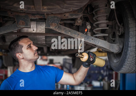 Auto master Mechaniker Werkstatt Heizung die Schrauben mit Butangas Schlag mini Schweißbrenner Flammenwerfer Brenner im Fahrzeug Reparatur Service Stockfoto