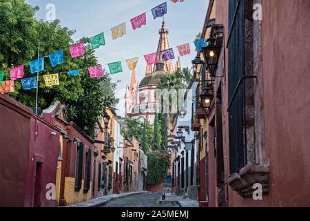 Kuppeln und Turmspitzen der Parroquia San Miguel Arcangel Kirche durch Papier Banner genannt Papel picado auf Aldama Straße im historischen Bezirk von San Miguel de Allende, Mexiko gesehen. Stockfoto