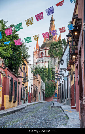 Kuppeln und Turmspitzen der Parroquia San Miguel Arcangel Kirche durch Papier Banner genannt Papel picado auf Aldama Straße im historischen Bezirk von San Miguel de Allende, Mexiko gesehen. Stockfoto