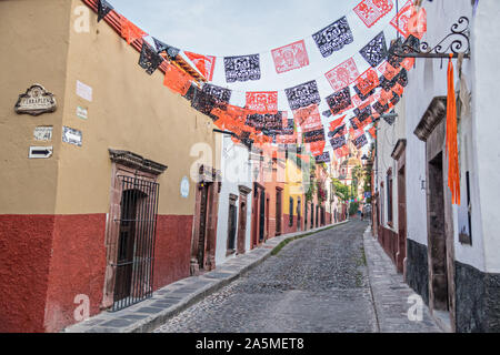 Kuppeln und Turmspitzen der Parroquia San Miguel Arcangel Kirche durch Papier Banner genannt Papel picado aufgereiht, der Tag der Toten Festival auf Aldama Straße im historischen Bezirk von San Miguel de Allende, Mexiko zu feiern gesehen. Stockfoto