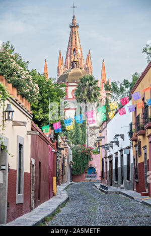 Kuppeln und Turmspitzen der Parroquia San Miguel Arcangel Kirche durch Papier Banner genannt Papel picado auf Aldama Straße im historischen Bezirk von San Miguel de Allende, Mexiko gesehen. Stockfoto