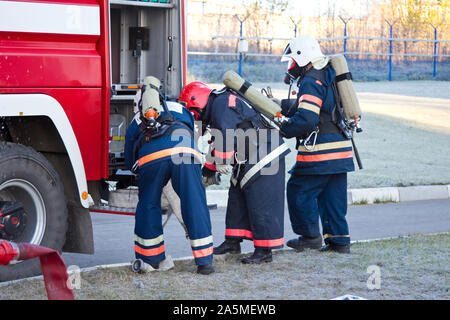 Gruppe von Feuerwehrleuten auf Gasmasken und Vorbereitung auf die Feuer löschen. Stockfoto