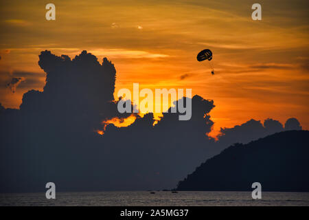 Super, eine wunderschöne und dramatische goldfarbenen Himmel hinter den Wolken bei einem atemberaubenden Sonnenuntergang während Tandem parasailers durch die magische Mom vorbei Stockfoto