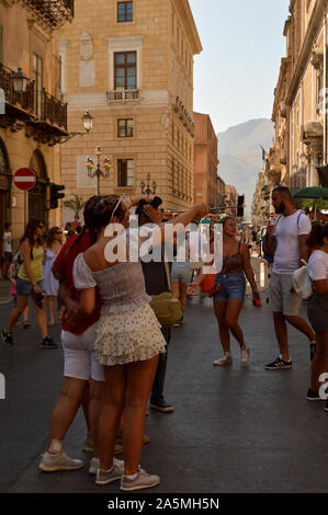 Touristen machen Fotos auf einer belebten Fußgängerstraße in Palermo, Sizilien, Italien, am 13. August 2019 Stockfoto