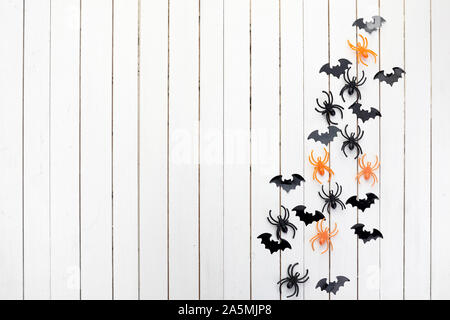 Halloween, Dekoration und beängstigend Konzept. Schwarzes Papier Fledermäuse und Spinnen auf weißem Holz- Hintergrund Stockfoto