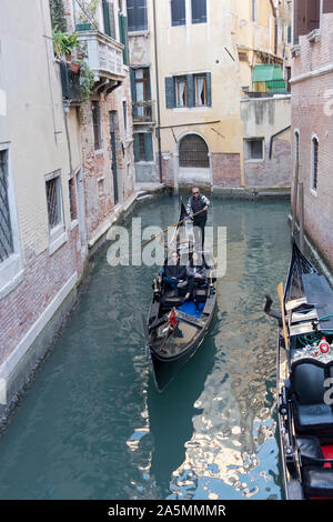 Eine asiatische Paar, voraussichtliche Chinesische, machen Sie eine Gondelfahrt in einer Seitenstraße Kanal in Venedig, Italien. Stockfoto