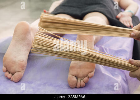 Massage mit Bambus der Füße. Eine entspannende und belebende Brasilianischen kreolische Massage. Lymphdrainage mit dünnen Bambus Besen. Stockfoto