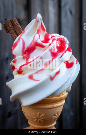 Leckeres Eis mit Himbeersauce und Schokolade gegen einen hölzernen Hintergrund. Stockfoto