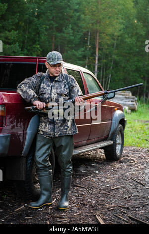 Jäger Tragen einer Brille und Camouflage mit Waffe Schrotflinte am Outdoor Jagd. Stockfoto