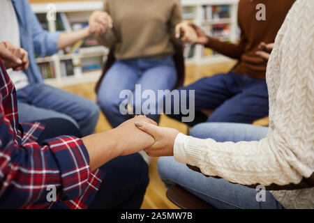 Nahaufnahme des unkenntlich Leute sitzen ion Kreis und halten sich an den Händen während der Sitzung der Gruppe, cpy Raum Stockfoto