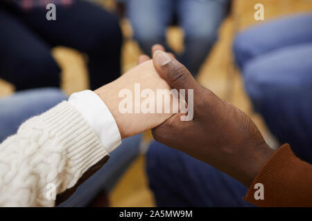Nahaufnahme des unkenntlich Leute sitzen ion Kreis und halten sich an den Händen während der Sitzung der Gruppe, cpy Raum Stockfoto
